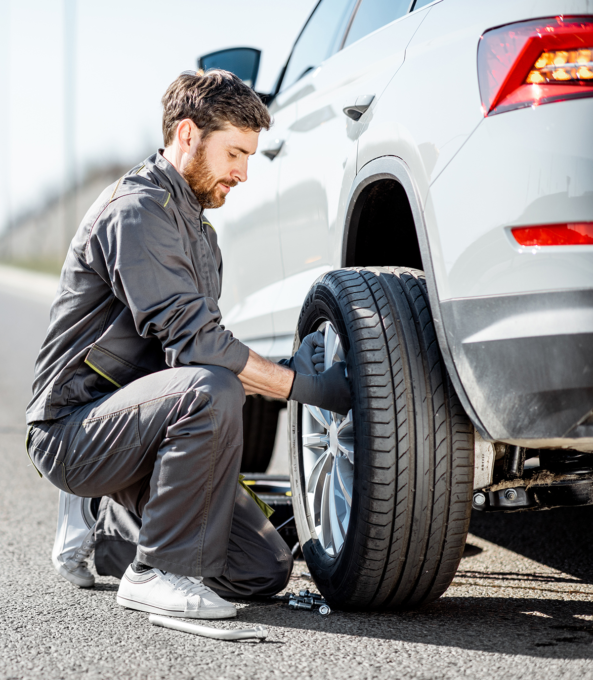 oseba menjuje pnevmatiko na avtomobilu